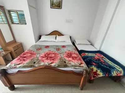 a bedroom with a bed with a floral comforter at D&D Residency in Mysore