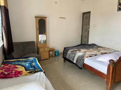 a bedroom with two beds and a chair and a mirror at D&D Residency in Mysore