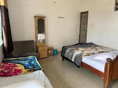 a bedroom with two beds and a chair and a mirror at D&D Residency in Mysore