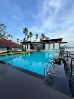 a large blue swimming pool with a house in the background at Aquatica Farms in Kodungallūr