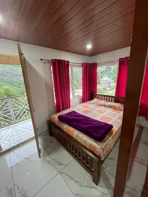 a bedroom with red curtains and a bed in a room at Joys Santa in Vattavada