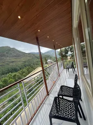 a balcony with a chair and a view of the mountains at Joys Santa in Vattavada