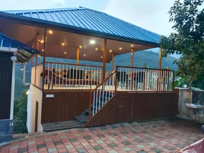 a house with a large deck with a blue roof at Joys Santa in Vattavada