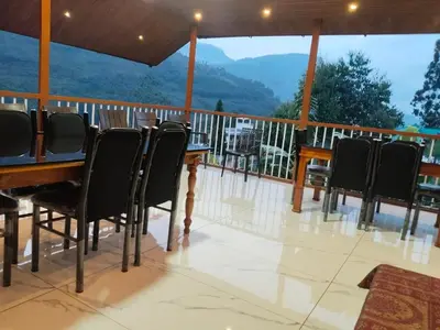 a deck with chairs and a table with a view at Joys Santa in Vattavada