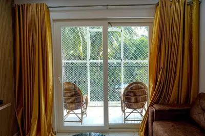 a room with a sliding glass door with two chairs at 1 BHK Luxury Flat in Samudhra Apartments-105 in Guruvāyūr