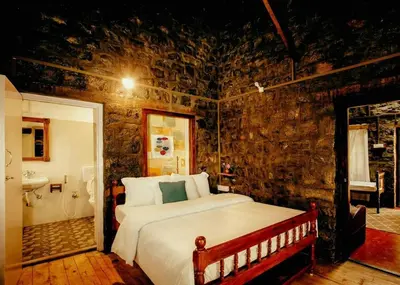 a bedroom with a bed in a stone wall at Atwood Chalet in Coonoor