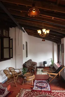 a living room with chairs and tables and a chandelier at Cinnamon Trails plantation bungalow in Kalpetta
