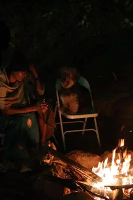 a woman and a dog sitting in a chair next to a fire at Cinnamon Trails plantation bungalow in Kalpetta