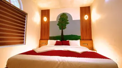 a bedroom with a bed with a tree painted on the wall at Karmalhills Homestay in Tindummal