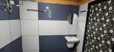 a blue and white bathroom with a toilet and a mirror at Karmalhills Homestay in Tindummal