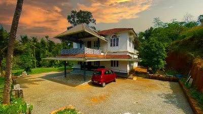 a red car parked in front of a house at Karmalhills Homestay in Tindummal