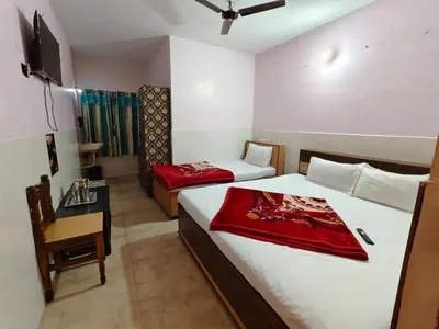 a bedroom with two beds and a table and a chair at Pillars residency in Ooty