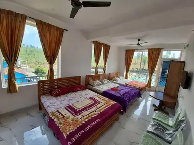 two beds in a room with a window at Stay41 in Vālpārai