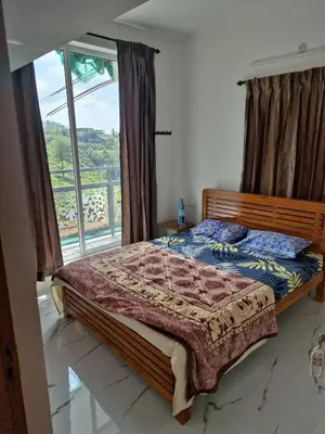 a bedroom with a bed and a large window at Stay41 in Vālpārai