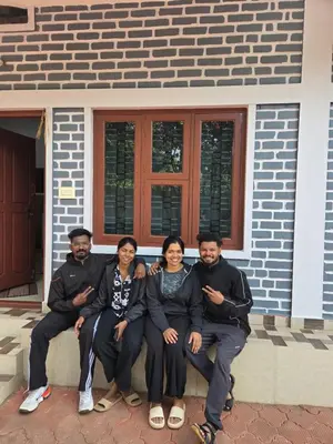 a group of people sitting in front of a house at Pearl Farmstay in Kushālnagar