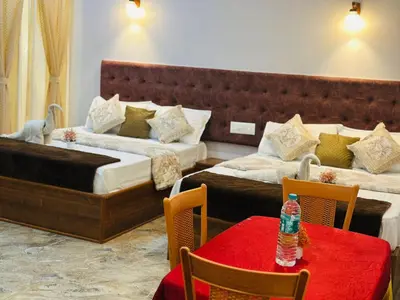 a hotel room with two beds and a table with a bottle of water at The Royal Palace & KGN Rooms & Restaurants in Belagula