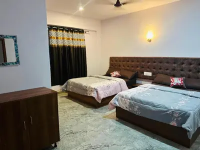a bedroom with two beds and a couch at The Royal Palace & KGN Rooms & Restaurants in Belagula