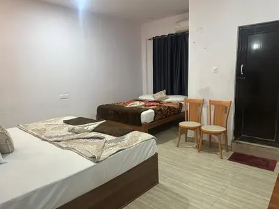 a hotel room with two beds and two chairs at The Royal Palace & KGN Rooms & Restaurants in Belagula