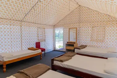 a room with three beds and a mirror at Coorg Kavery Estate by Aarika Resorts in Napoklu