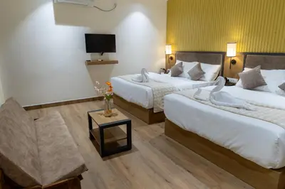 a hotel room with two beds and a tv at Coorg Kavery Estate by Aarika Resorts in Napoklu