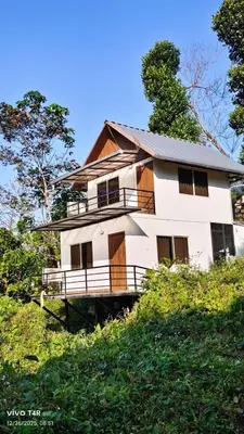 a large white house on a hill with trees at River bendHome in Viripara