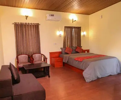a bedroom with a bed and a chair and a couch at Rippon Mount Resorts in Meppādi