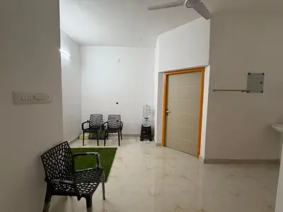 a room with chairs and a door and a green rug at ACK River Palms - Athirappilly in Athirappally