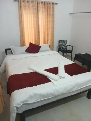 a bedroom with a large bed with red and white sheets at ACK River Palms - Athirappilly in Athirappally