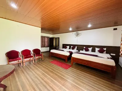 a bedroom with two beds and two red chairs at Phalam Homestay in Kushālnagar