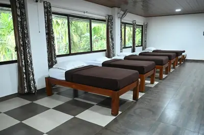 a row of beds in a room with windows at Phalam Homestay in Kushālnagar