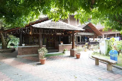 a building with a pavilion with plants in front of it at Mango Village Resort in Kollengode