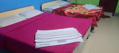two beds with pink sheets and white towels on them at Friends Residency Mysuru in Mysore