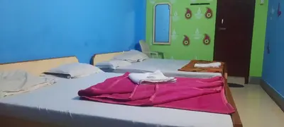 two beds in a room with purple sheets on them at Friends Residency Mysuru in Mysore