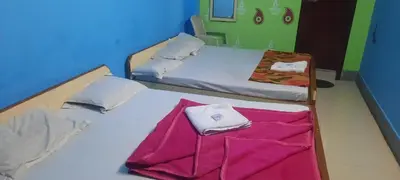 two twin beds in a room with a pink blanket at Friends Residency Mysuru in Mysore