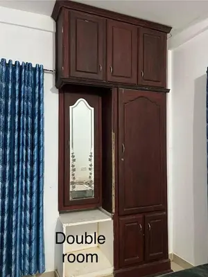 a wooden cabinet with a mirror in a room at Vrindhavan stay and rooms in Guruvāyūr