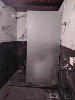 a bathroom with a shower with a metal door at Golden Valley Abode in Siddapur