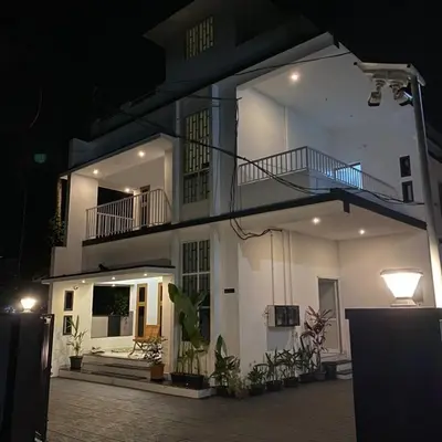 a large white building with a balcony at night at KM Villa in Kottakkal