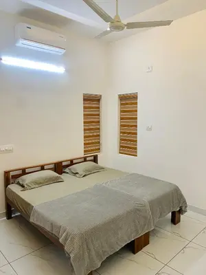 two beds in a white room with a ceiling fan at KM Villa in Kottakkal