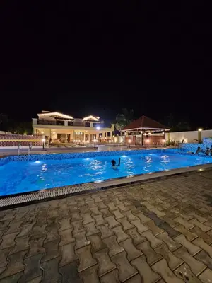 a swimming pool at night with a building in the background at Kurunchi Malar Resorts in Hosūr