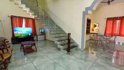 a living room with a staircase and a television at The Cove, ' the silent Symphony ' in Parassinikadavu