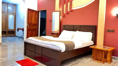 a bedroom with a bed with a red wall at Royal Rivera Holiday Home in Kalpetta