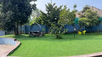 a yard with green grass and trees and a fence at Royal Rivera Holiday Home in Kalpetta