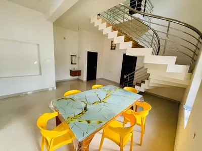 a dining room with a glass table and yellow chairs at Ocean pearl homestay-pariyaapuram