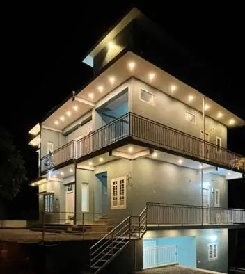 a large house with lights on it at night at The Karlyle Homestay in Sultan Bathery