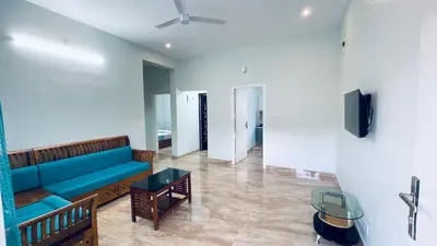 a living room with a blue couch and a tv at The Karlyle Homestay in Sultan Bathery