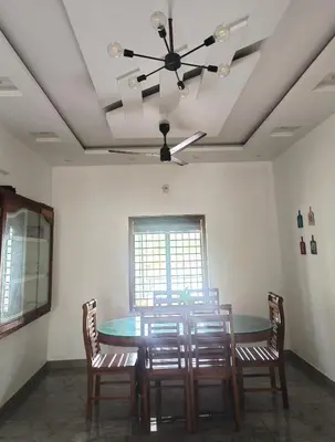 a dining room with a table and chairs and a ceiling fan at Riverfront Villa in Kochi in Kodungallūr