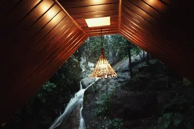 a room with a view of a forest with a chandelier at Hornbill Paradise, Munnar in Viripara