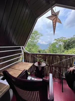 a room with a table and chairs on a balcony at Hornbill Paradise, Munnar in Viripara
