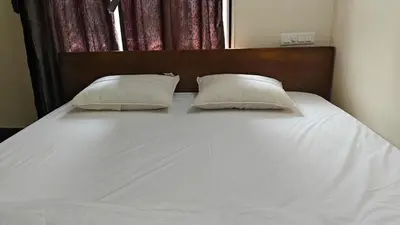 a large white bed with two pillows on it at Gamani in Mysore