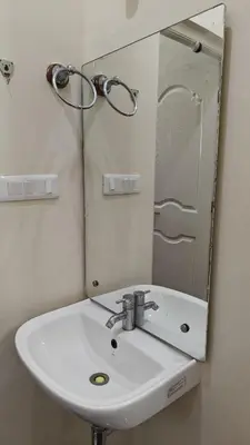 a bathroom with a white sink and a mirror at Gamani in Mysore